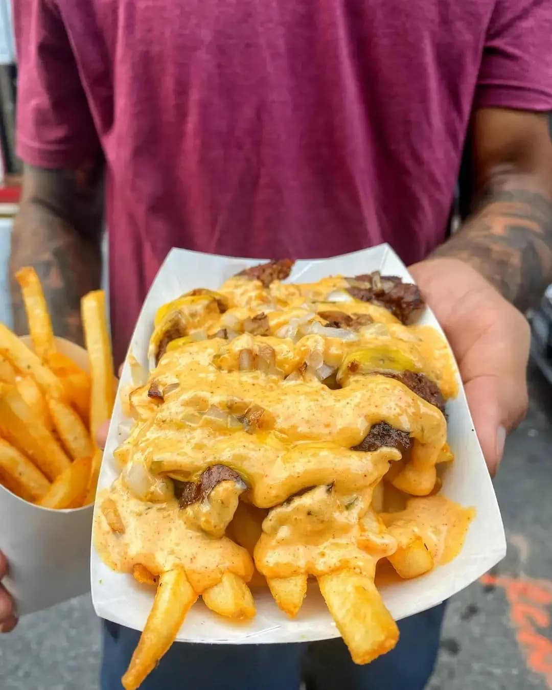 Close-up of loaded fries topped with melted cheese, grilled onions, and special sauce from 7th Street Burger.